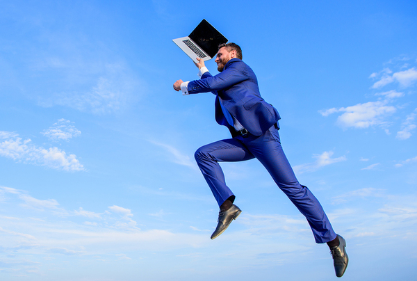 Man jumping in the air with a laptop.