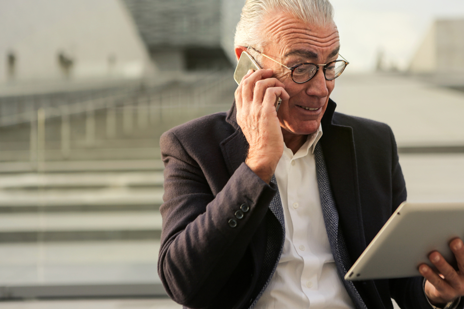 Man looking at a tablet while talking on the phone.