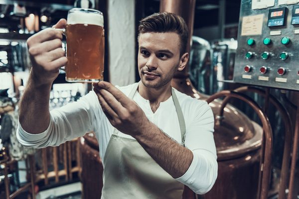 Craft brewer looking at a sample of beer.