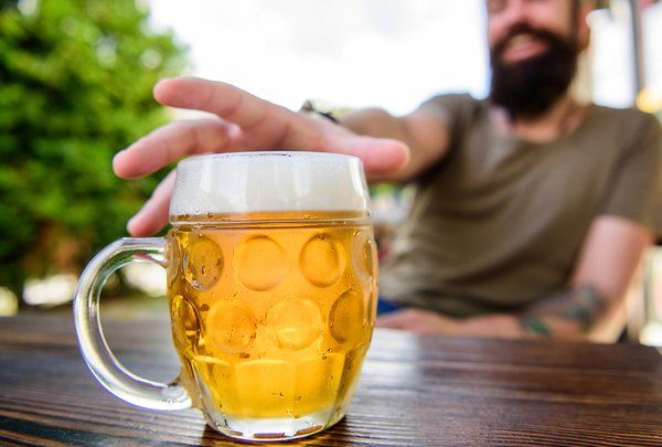 Man reaching for a mug of beer.