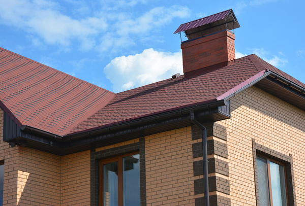 Brick home with red roof and black gutters.