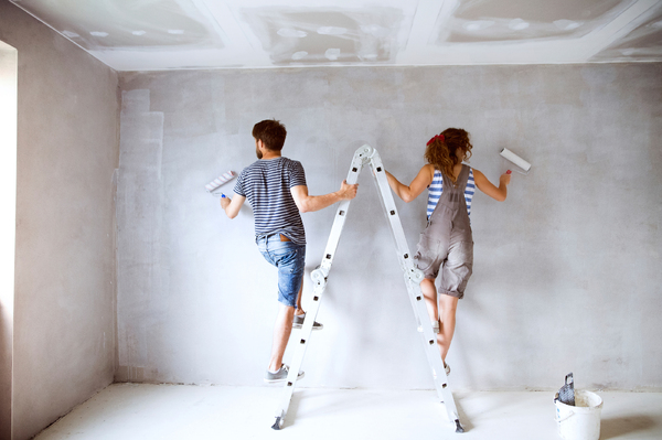 Couple on a ladder painting a wall.