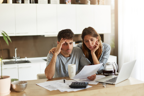 Couple sitting at a counter with documents and a laptop.