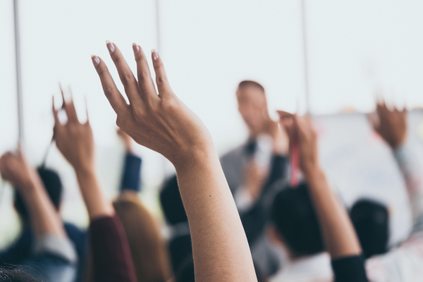Group of people raising their hands at a seminar.