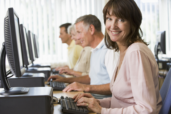 Group of people sitting in front of desktop computers.