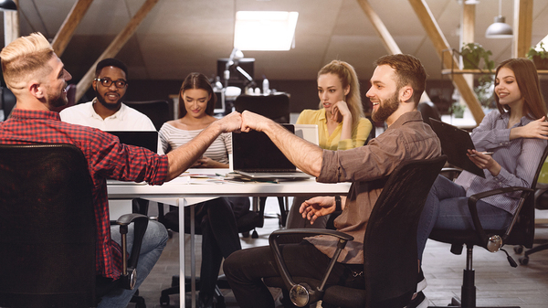 Group of people working and giving fist bumps.