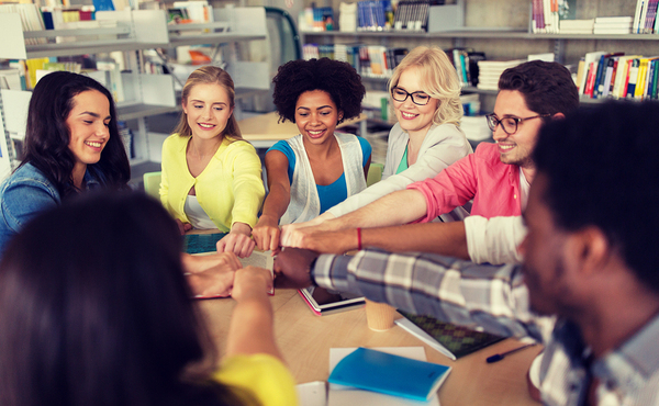 Group of people in a circle with hands in the center.