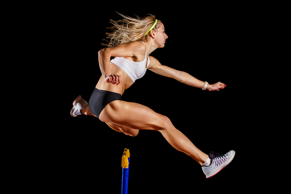 Woman jumping over a hurdle.