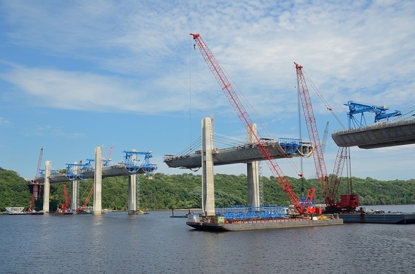 Construction of bridge over water with barges and cranes.