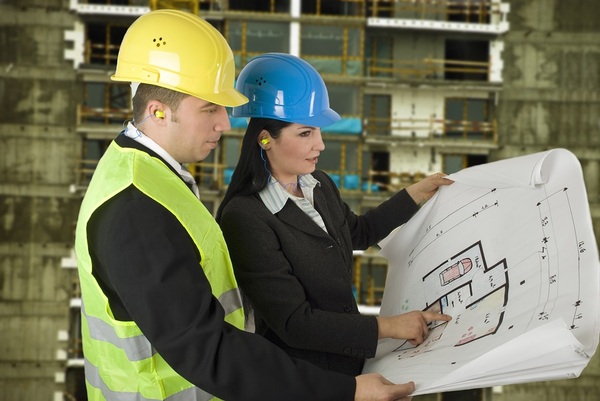 Construction workers with hard hats on looking at building plans.