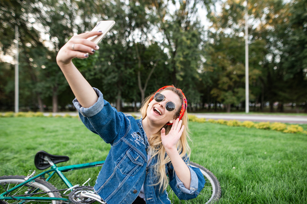 Woman taking a selfie outside next to a bicycle.