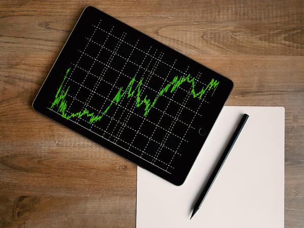 Tabletop with a tablet displaying graphical data in an upward swing.