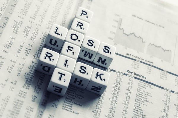 The words profit, loss, and risk created with white dice.