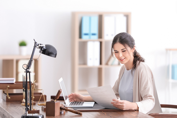 Person working at a desk with their laptop and document.