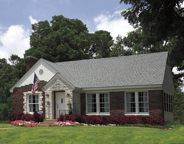Red brick front home with grey shingled roof.