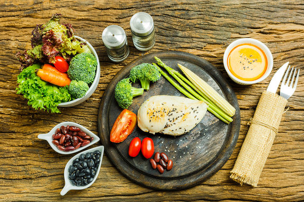 Table top with chicken dinner including vegetables and legumes.