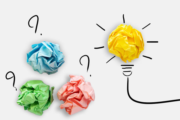 Crumpled up colored papers, and one yellow colored paper creating a lightbulb.