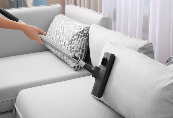 Person vacuuming a couch.