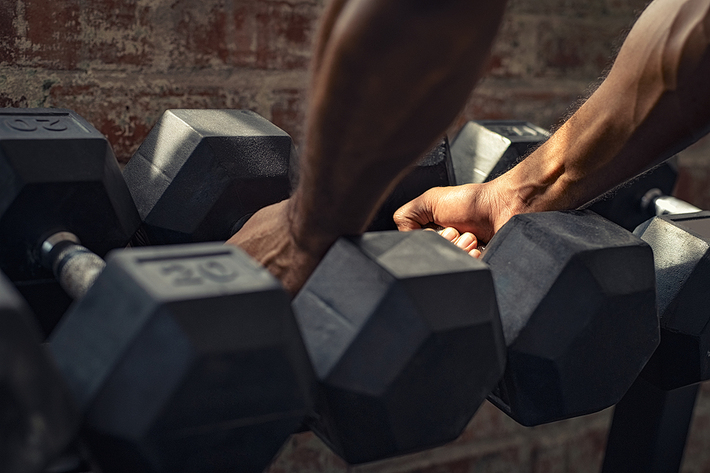 Reaching for a set of dumbbells.