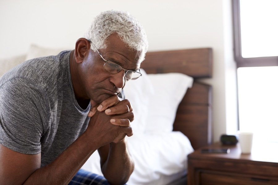 Man sitting at the edge of his bed.