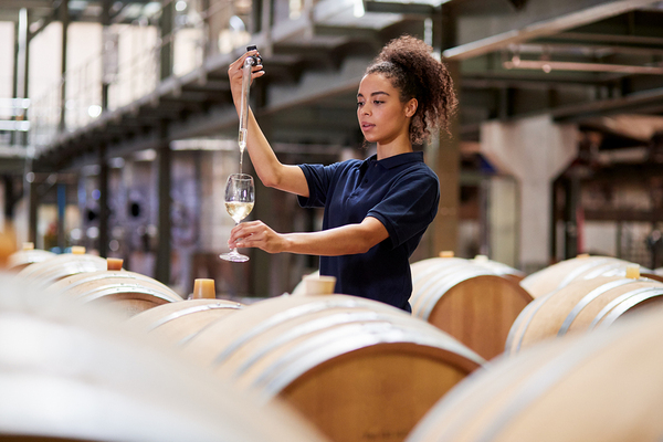 Woman pouring a glass of wine from a barrel.