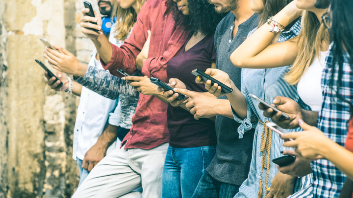 Group of people standing using their mobile phones.