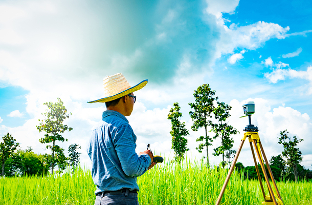 Land surveyor working in a grassy field.