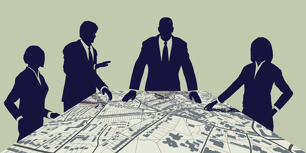 Group of people around a table looking at a large map.