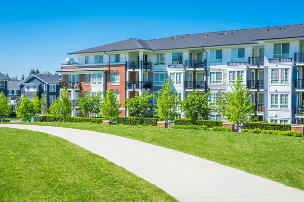View of condominiums with a pathway in front and green grass.