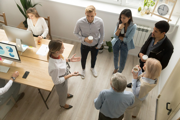 Group of colleagues standing around drinking coffee and discussing innovation ideas.