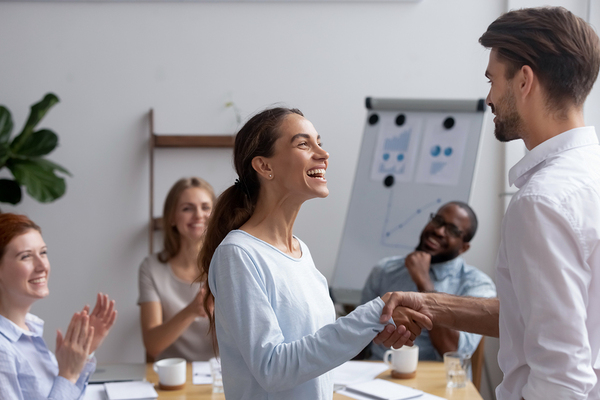 Group of colleagues clapping and smiling while working together.
