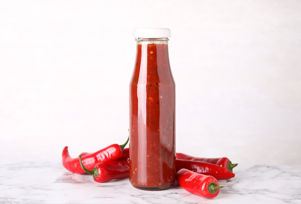 Glass bottle filled with red peppers.