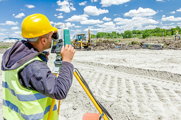 Engineer using surveying equipment at a construction site.