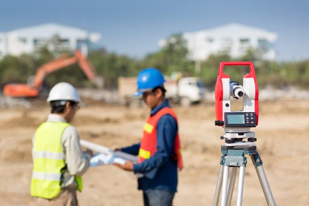 Two men with hardhats and reflective vests looking at engineering plans.