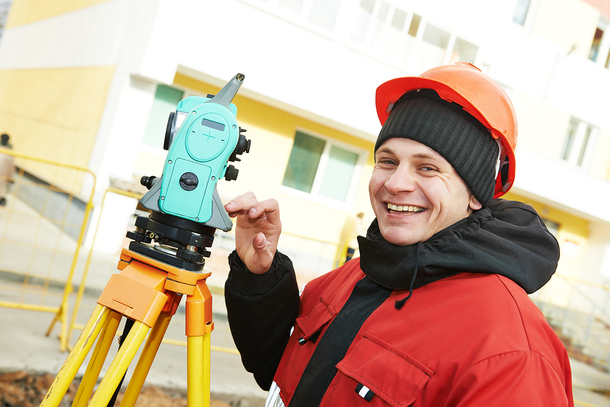 Man with a hardhat and land surveying equipment.
