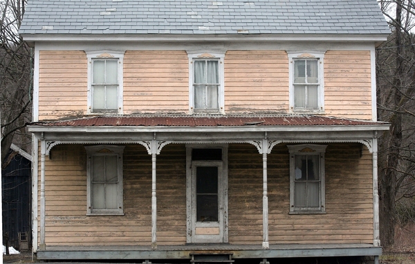 Older house with peeling pain and loose roof shingles.