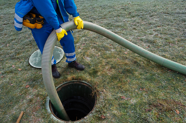 Worker pumping out a septic tank.