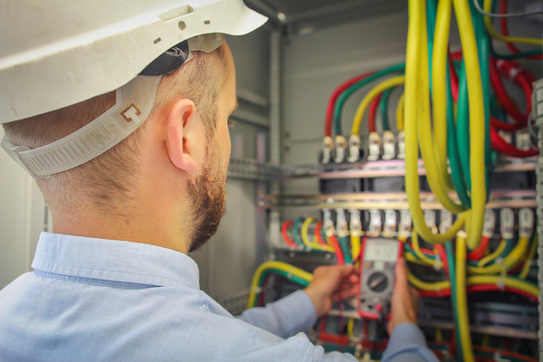 Man with a white hardhat working on electrical box.