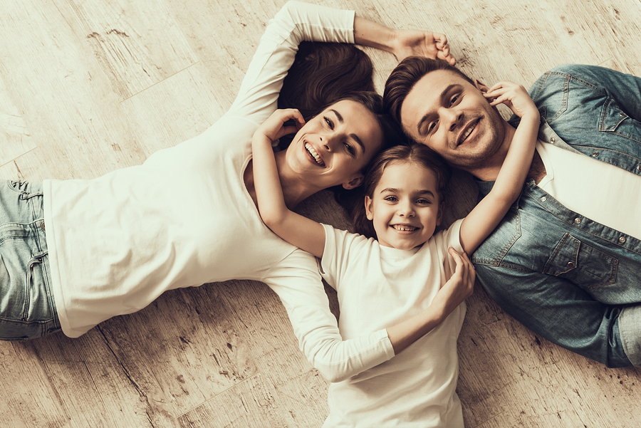A family of three lying on the floor smiling.