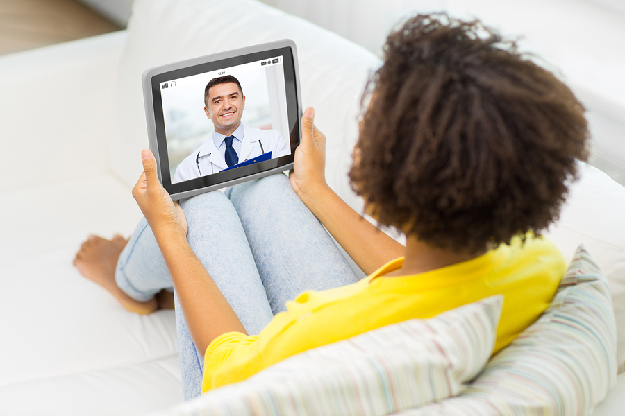 Woman sitting on a couch having a teleconference with a medical doctor.