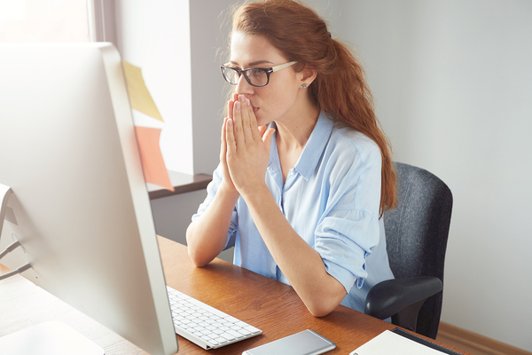 Woman sitting in front of her desktop computer smiling.