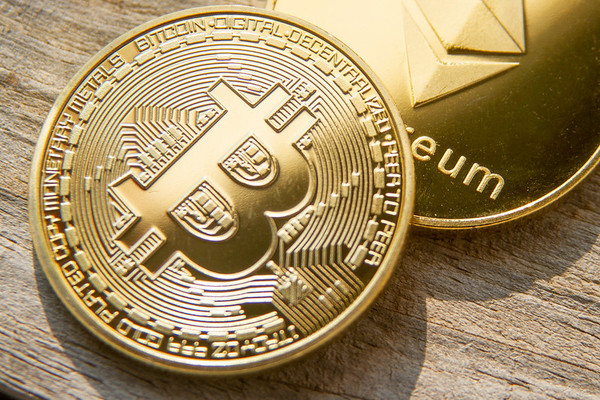 Gold coins one with a bitcoin symbol and the other with ethereum symbol.