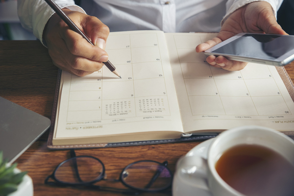 Person writing in a monthly planner notebook.