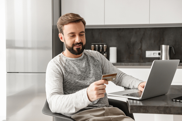 Man paying for goods using a credit card and his laptop.