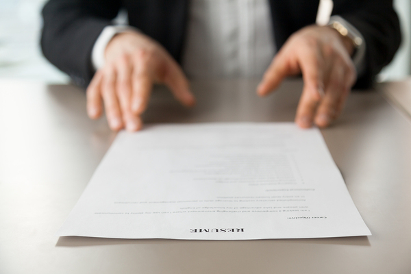 Man in a business suit looking at a resume.