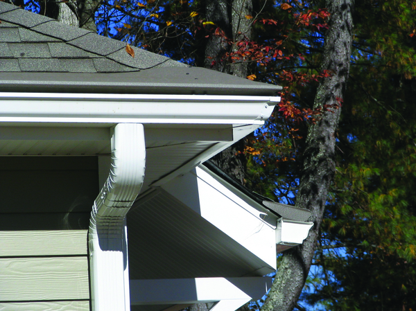 Corner of a home with white gutters and downspout.