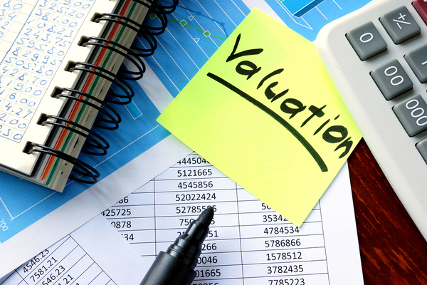 Notebook and documents on a desk with a sticky note labeled valuation.