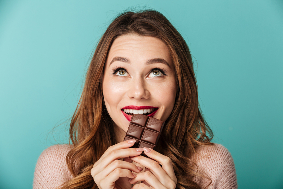 Happy woman biting into a piece of chocolate.