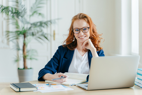 Woman smiling while writing in a notebook.