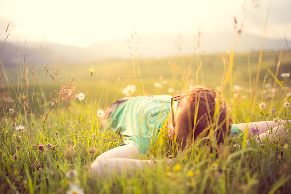 Person lying down in the grass looking up at the sky.